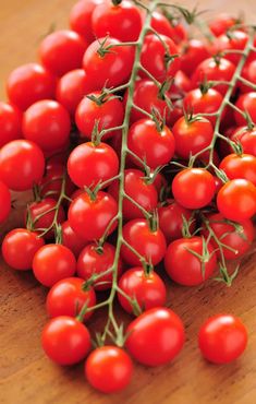 a bunch of red tomatoes sitting on top of a wooden table