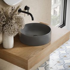 a bathroom sink sitting on top of a wooden counter next to a vase with flowers