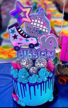 a birthday cake decorated with disco balls and decorations on a blue tablecloth covered table