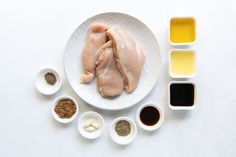 a white plate topped with chicken wings next to bowls of seasoning