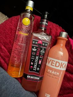 three different types of alcohol sitting on top of a red blanket next to each other