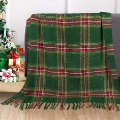 a green plaid blanket sitting on top of a wooden floor next to a christmas tree