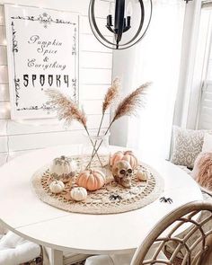 a white table topped with lots of pumpkins and other decorating items next to a chandelier