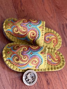 a pair of yellow shoes sitting on top of a wooden floor next to a coin