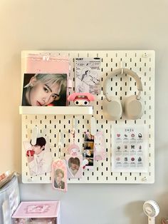 a white pegboard with pictures and magnets attached to it next to a desk