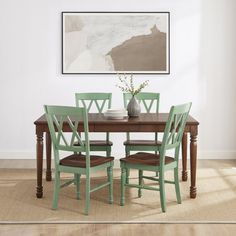 a dining room table with four chairs and a vase on top of it in front of a white wall