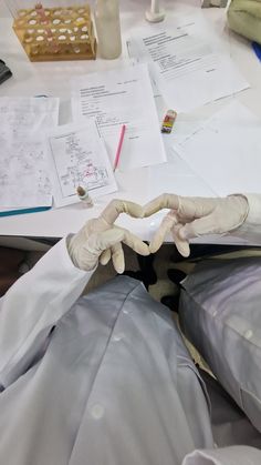 someone in white gloves making a heart shape with their hands at a table full of papers