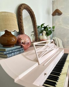 a white piano sitting on top of a table next to a lamp