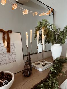 a table topped with candles next to a mirror and potted plant on top of it