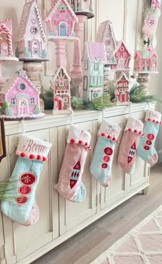 christmas stockings hanging from the wall in front of a fireplace with gingerbread houses on it