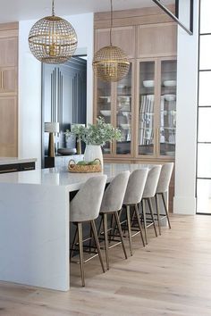 a kitchen with wooden cabinets and white counter tops, along with beige bar stools