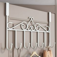 a white coat rack with four hooks and two purses