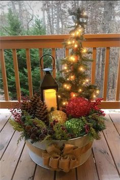 a christmas tree in a bucket on a deck with lights around it and presents under the tree