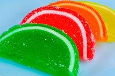 four different colored candies sitting on top of a blue tablecloth covered in powdered sugar