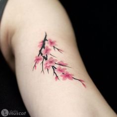 a tattoo with pink flowers on the left side of the arm and behind it is a black background