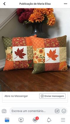 two pillows sitting on top of a table next to a vase with flowers in it