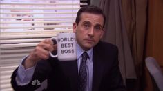 a man holding up a coffee mug with the words world's best boss on it