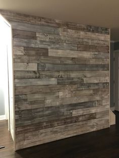 an empty room with wood planks on the wall and hard wood flooring in it