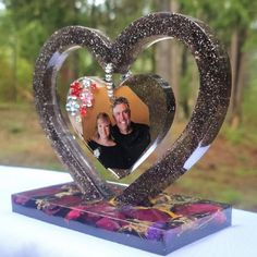 a man and woman are in a heart - shaped photo frame on top of a table