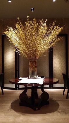 a vase with flowers on top of a table in front of some chairs and tables