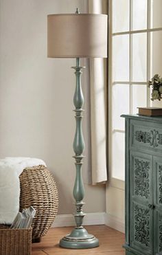 a lamp that is on top of a table next to a dresser and chair in a room