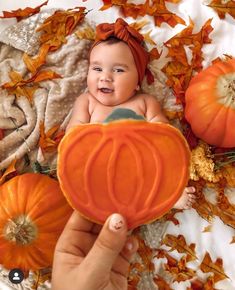 a baby is sitting in a pumpkin - shaped bowl surrounded by fall leaves and fake pumpkins