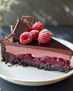 a piece of chocolate cake with raspberries and chocolate on the top is sitting on a plate