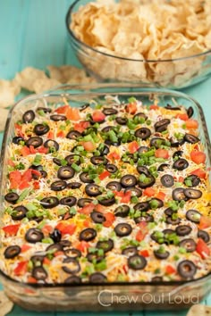 a casserole dish with olives, carrots, and peas in it