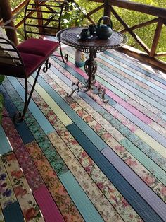 a table and chair sitting on a wooden deck with colorful strips of wood covering it