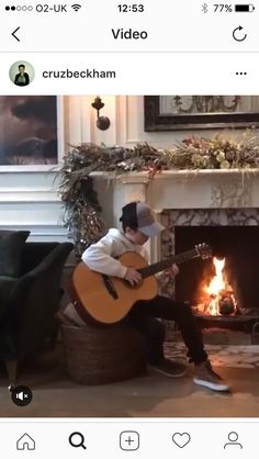 a man sitting in front of a fire holding a guitar