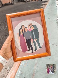 a person holding up a framed photo with people on it in front of a building