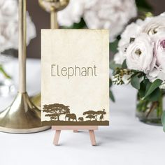 there is a sign that says elephant on it next to some flowers and vases