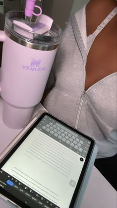 a woman holding a tablet next to a pink coffee cup