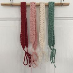 four crocheted headbands hanging from a hook on a white door hanger