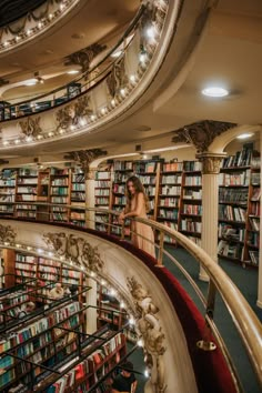 a woman is standing in the middle of a library full of books and looking down at it