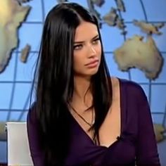 a woman with long black hair is sitting in front of a news desk and looking off to the side