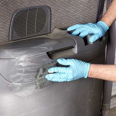 a person in blue gloves is cleaning the back of a car