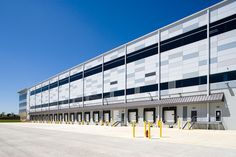 an empty parking lot in front of a large building with many windows and doors on each side