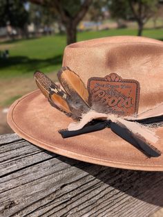 Coors Cowboy meets rancher hat!  Leather Coors Cowboy Patch on a wide brim rancher hat. Hand burned edges to look aged.  Layered soft fabric with silver chain band and naturally sourced feathers. ADD ON OPTIONS:  Want your initials added to the chain band for a custom hat!   This is a Vegan Suede Rancher Hat in tan color -hand burned to look aged This hat is one size fits most, Medium,  with an elastic inner band to fit size 55-59cm or  7 - 7¼  This hat is ready to ship. NOTICE OF NON-AFFILIATION AND DISCLAIMER: We are not affiliated, associated, authorized, endorsed by, or in any way officially connected with the brand shown or any of its subsidiaries or its affiliates. All related names, marks, emblems and images are registered trademarks of their respective owners. These are not officia Rustic Fedora With Flat Crown For Country Events, Rustic Style Hat Bands For Kentucky Derby, Rustic Brimmed Hat Band For Kentucky Derby, Rustic Wide Brim Hat Bands For Kentucky Derby, Country Style Fedora With Flat Crown For Country Events, Rustic Flat Brim Fedora For Kentucky Derby, Rustic Brimmed Fedora For Country Events, Rustic Fedora For Country Events, Rustic Felt Hat For Rodeo With Flat Crown