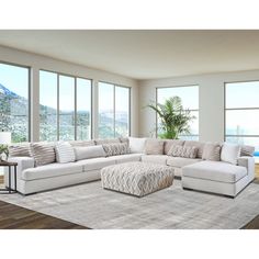 a living room with large windows and a white couch in front of the window is an ottoman