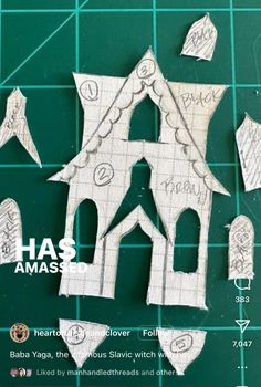 paper cut out of the shape of a house on top of a green cutting mat