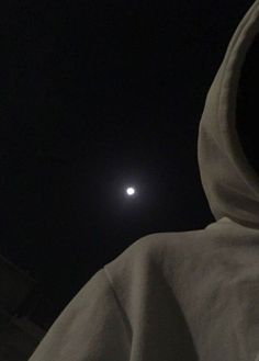 a person wearing a hooded jacket with the moon in the background