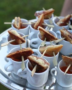 small cups with toothpicks sticking out of them on a silver tray in the grass