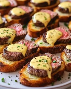 small pieces of bread topped with steak and hollandaise sauce on top of it