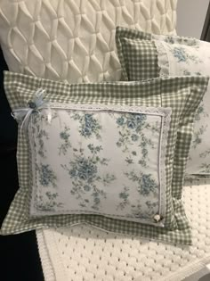 two pillows sitting on top of a bed next to a pillow case with blue flowers