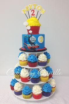 a thomas the train birthday cake with cupcakes and decorations on it's tier