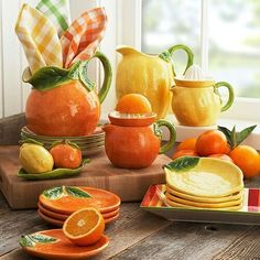 oranges, lemons and other fruit are arranged on a wooden table with dishes