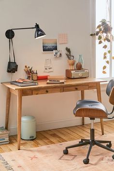 a room with a desk, chair and lamp on it in front of a window