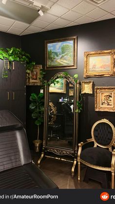 a room with black walls and paintings on the wall, including a gold framed mirror