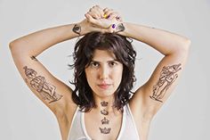 a woman with tattoos on her arms and chest posing for the camera while holding her hands behind her head